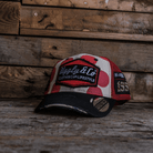 Front view of a trucker hat with red and white polka dot design and signature Uggly&Co logo on a wooden background