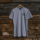 Front view of the Keep it Lit Uggly&Co grey t-shirt on a wooden background