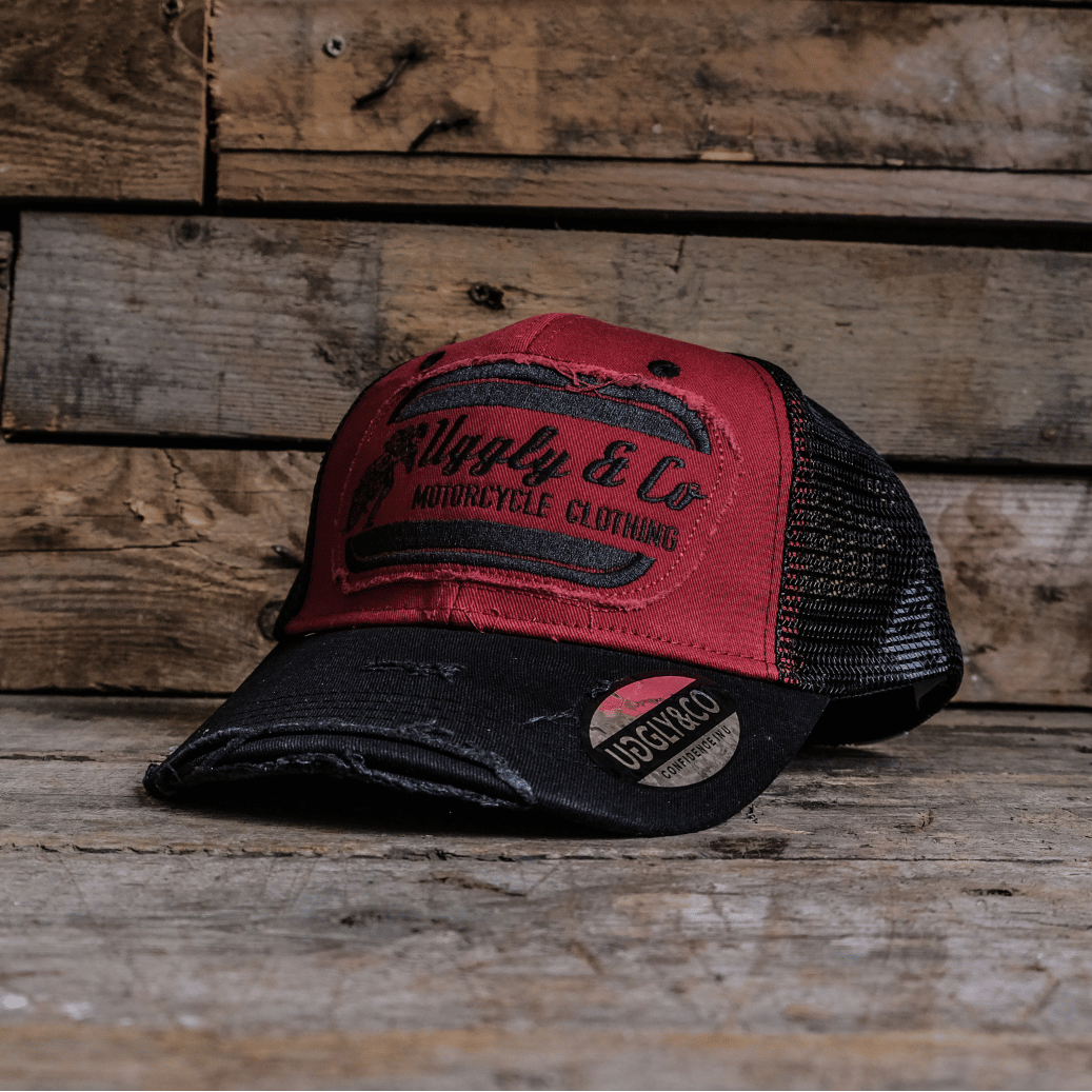 Red and black trucker hat with branding on a wooden surface