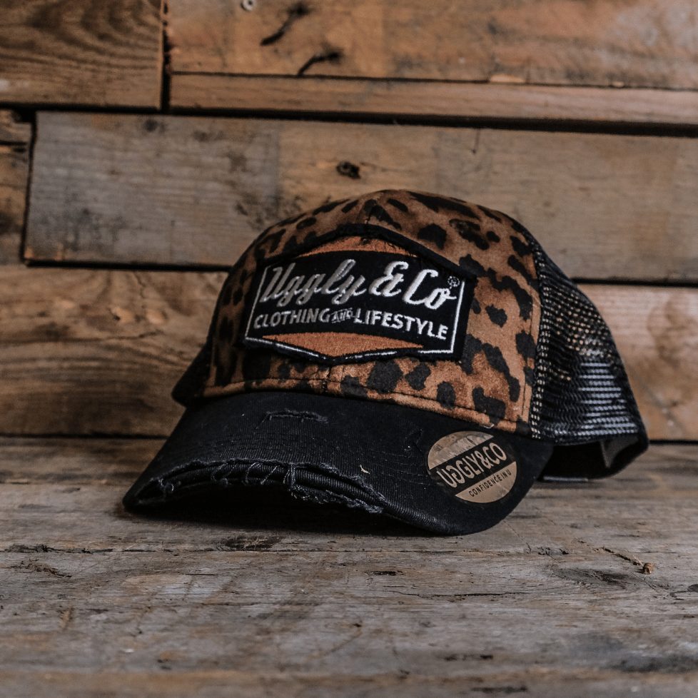 Leopard print trucker hat with black mesh back on a wooden surface