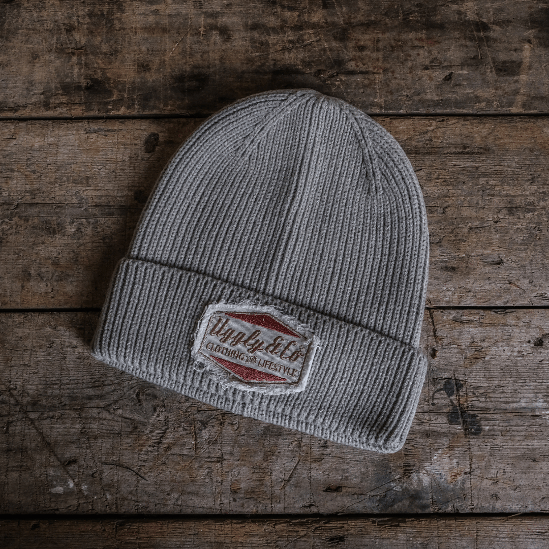 Gray beanie with a brand patch on a wooden surface
