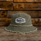 Frayed green bucket hat with an Uggly&Co diamond logo on a wooden background