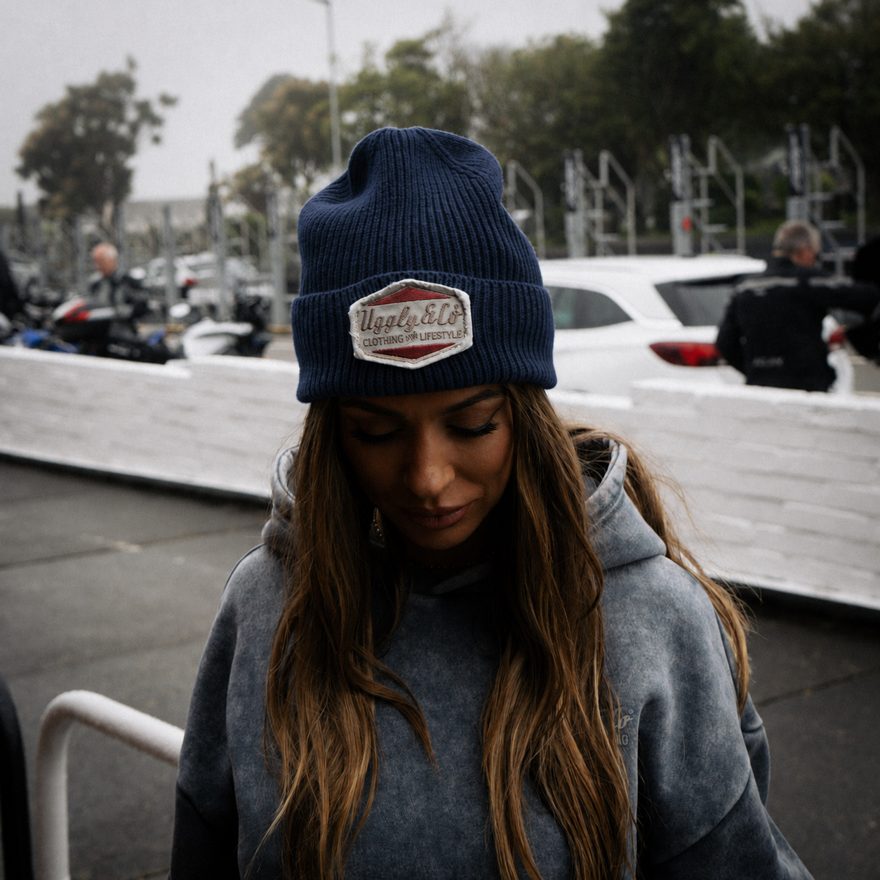 female model wearing a blue beanie next to a race track
