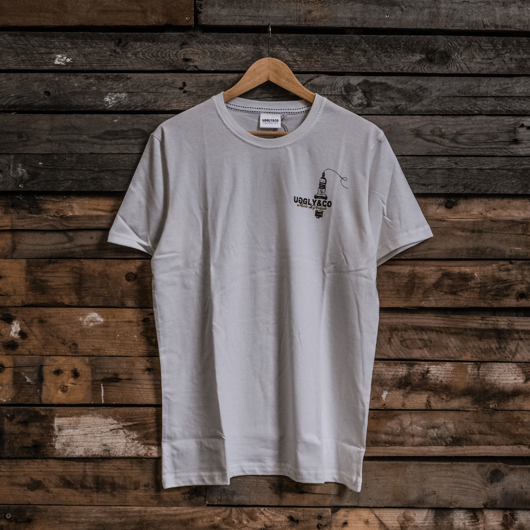 Front view of a limited edition Valentine’s white t-shirt with spark plug heart graphic, and Uggly&Co logo on a wooden background