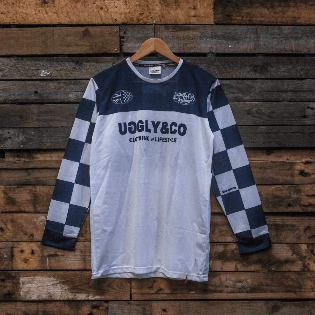 Checkered long-sleeve MX shirt with 'Uggly & Co' branding on a wooden background facing forwards