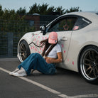Female model wearing the Washed Pink Vintage Cap in an automotive lifestyle scene