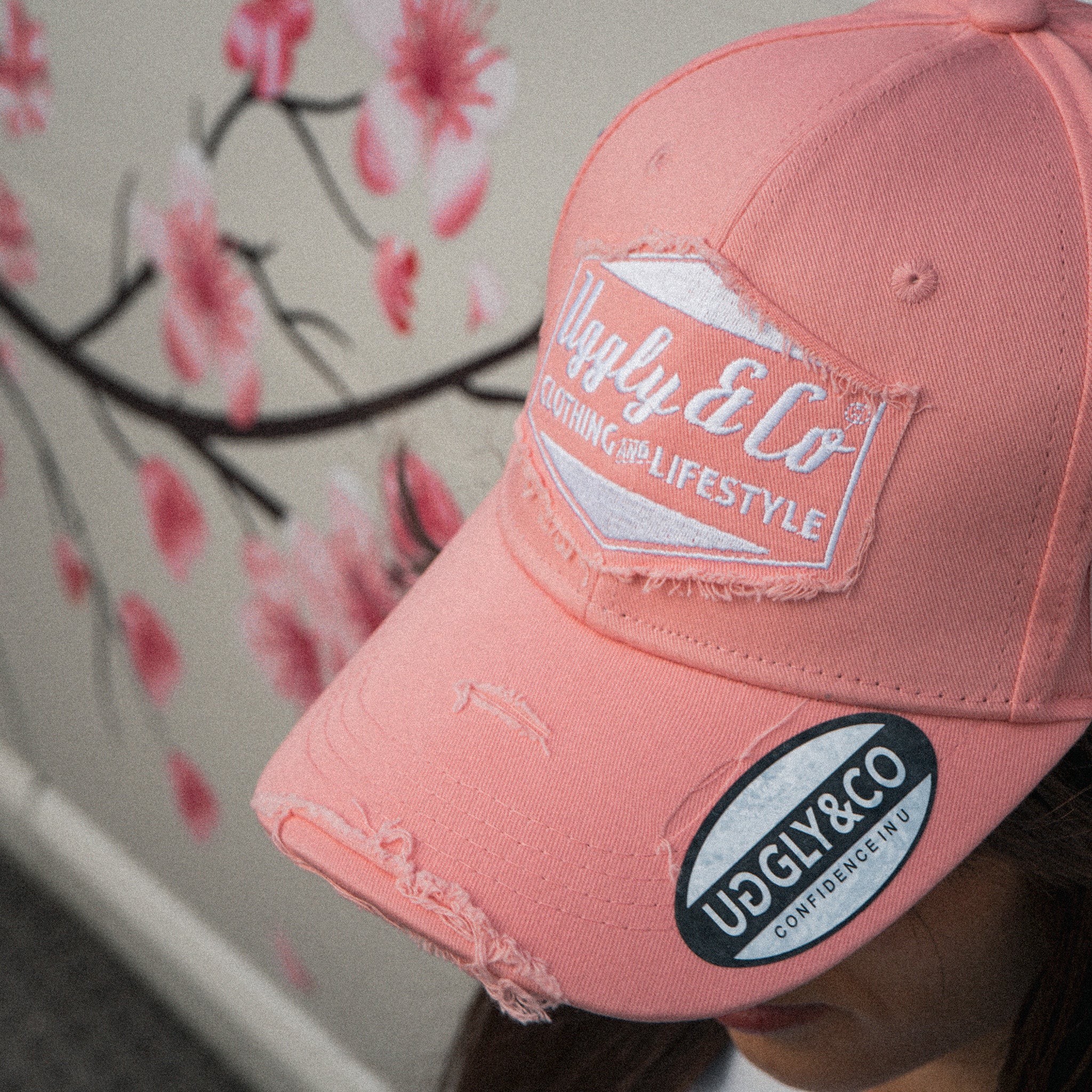 Close up detail of a female model wearing the Washed Pink Vintage Cap with a modified car behind her