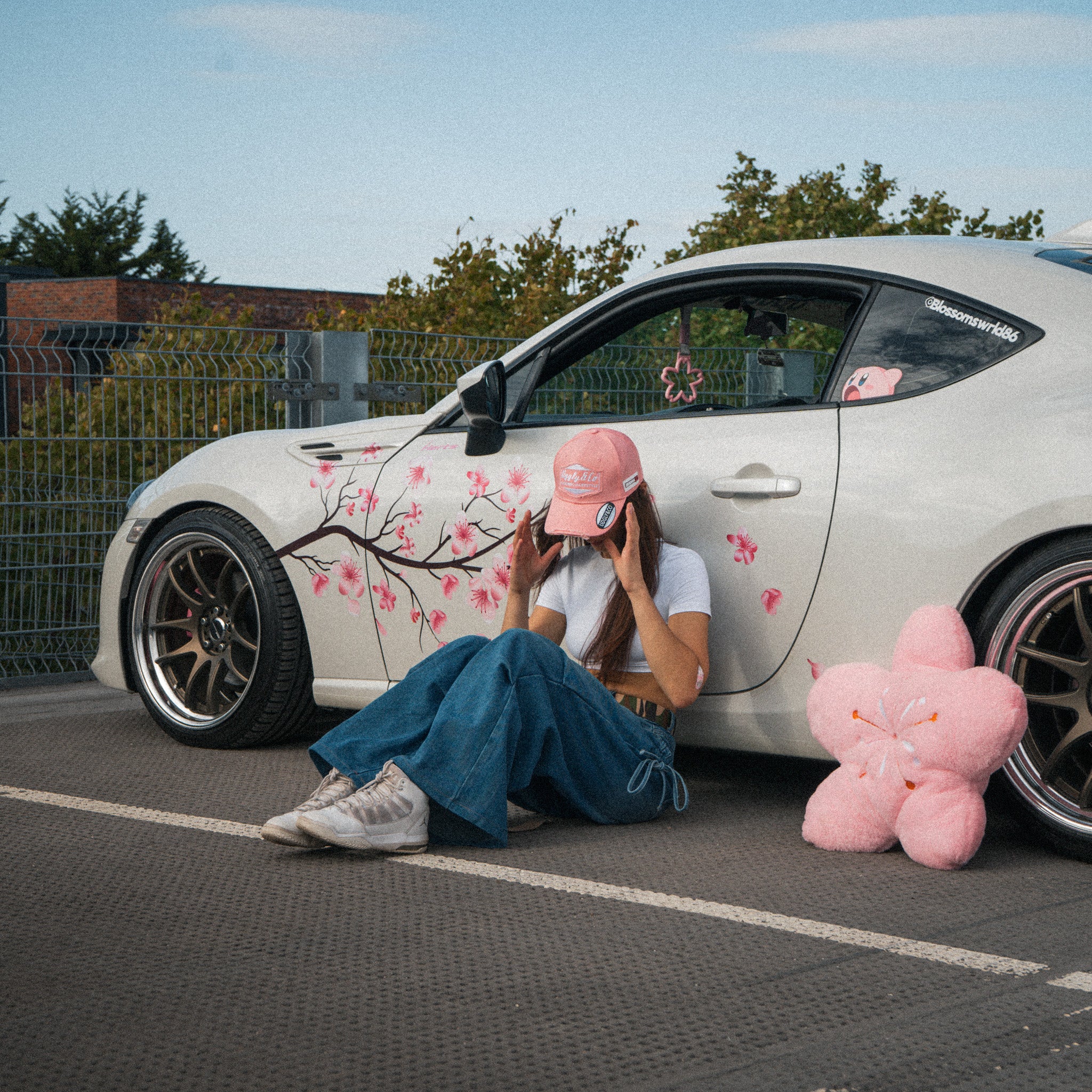 Female model wearing the Washed Pink Vintage Cap in front of a modified car
