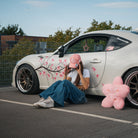 Female model wearing the Washed Pink Vintage Cap in front of a modified car