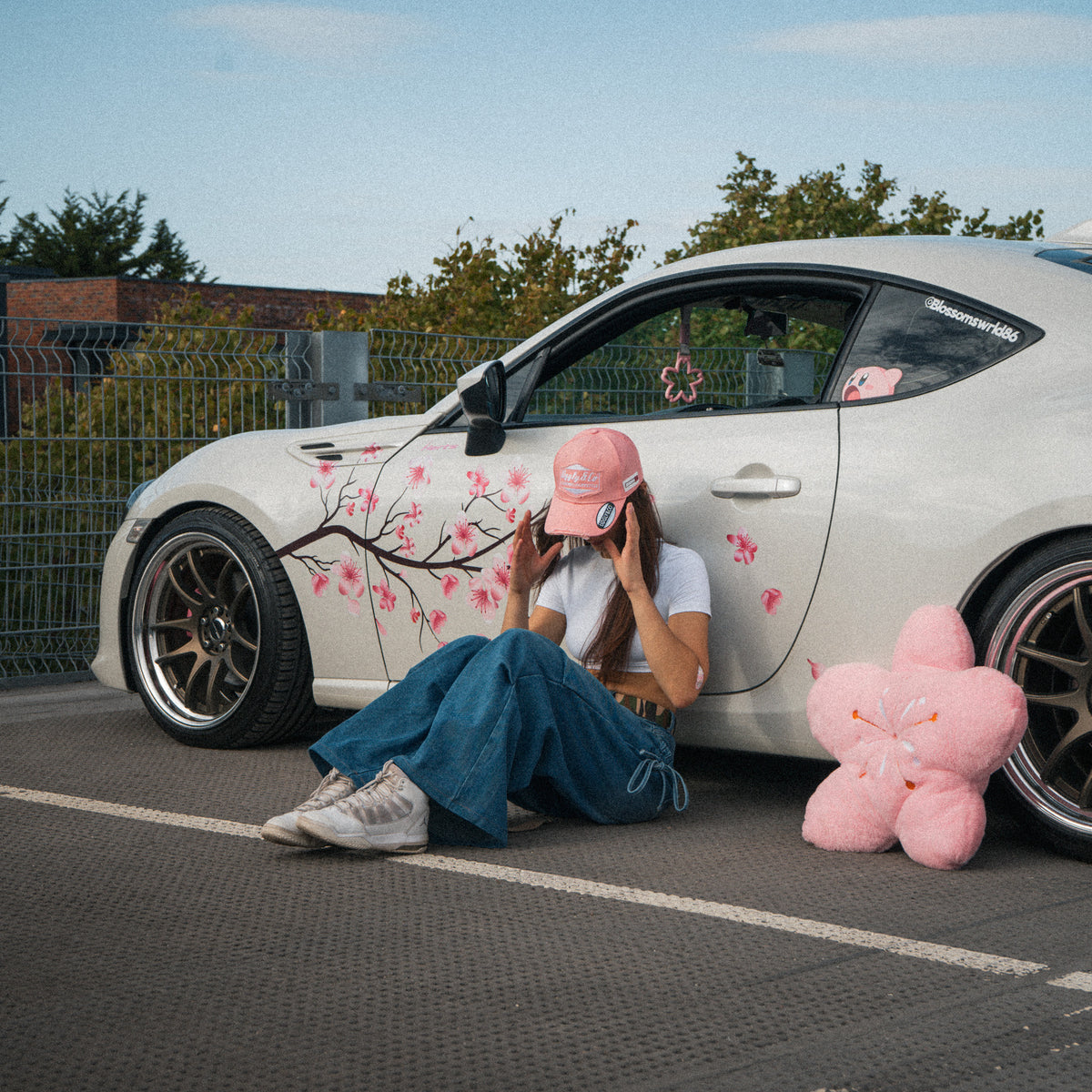 Female model wearing the Washed Pink Vintage Cap in front of a modified car
