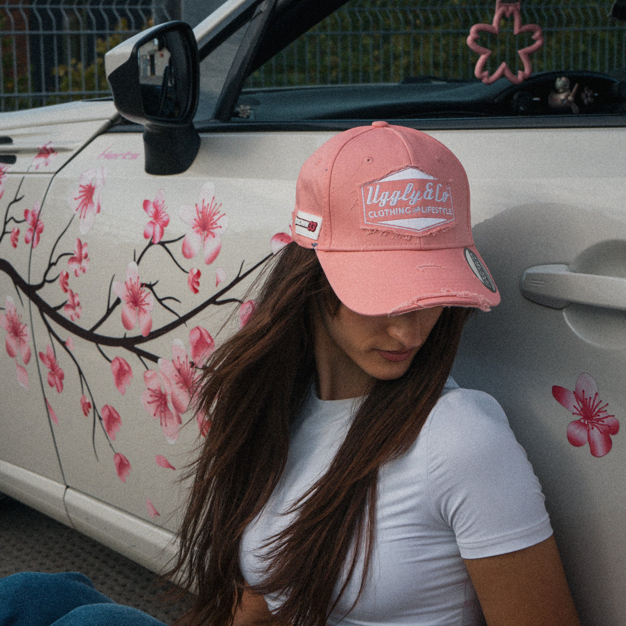 Female model styling the Washed Pink Vintage Cap with a modified car in a streetwear setting