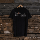 Rear view of a black t-shirt with a motorcycle, love heart and spark plug graphic on a wooden background